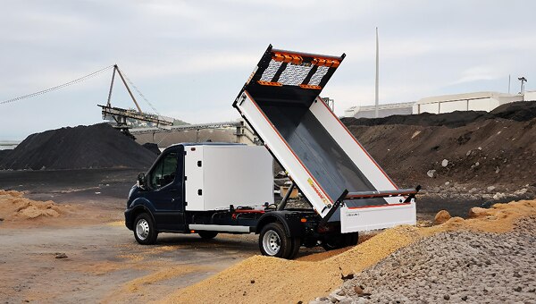 Camião basculante Ford Transit descarregando materiais em obra.
